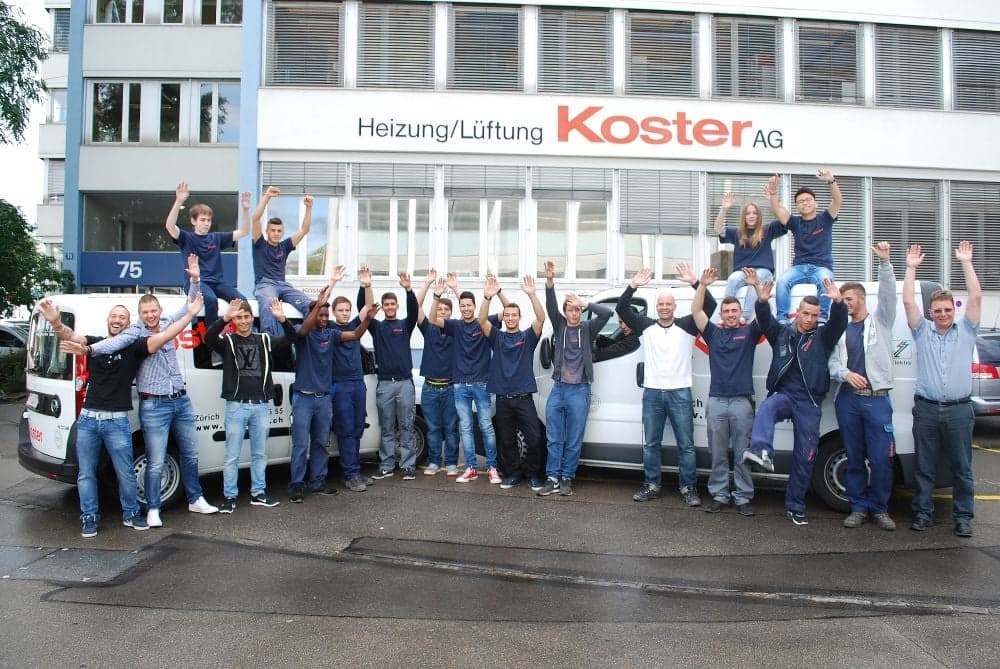 Mitarbeitende der Koster AG vor dem Firmengebäude in Zürich, mit den Servicefahrzeugen.